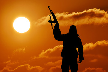 Fototapeta na wymiar Silhouette of soldier officer with weapons at sunset