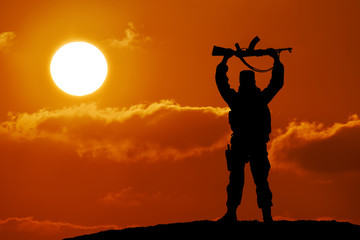 Silhouette of soldier officer with weapons at sunset