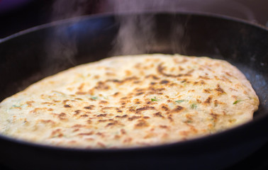 Thin pie with herbs and cheese in a pan