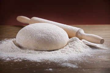 wooden rolling pin with dough and dusting of flour.