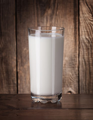 Fresh milk in a glass on old boards