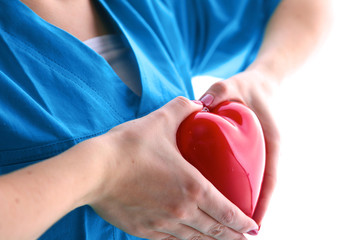 Female doctor with stethoscope holding heart over white