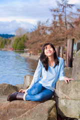 Fototapeta na wymiar Happy young teen girl face upturned, smiling, while sitting outd
