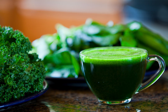 Glass cup of green vegetable juice on kitchen counter