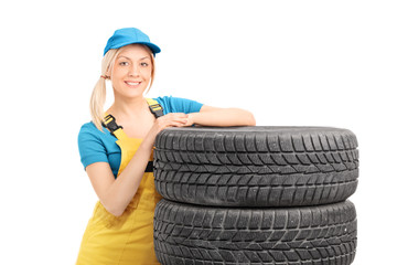 Female mechanic leaning on a stack of used tires