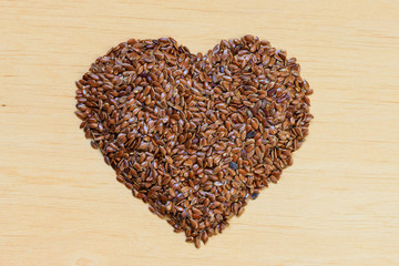 Raw flax seeds linseed heart shaped on wooden table