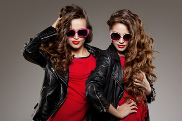 Sisters twins in hipster sun glasses laughing Two fashion models