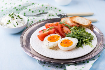Breakfast with soft-boiled egg, arugula and tomatoes