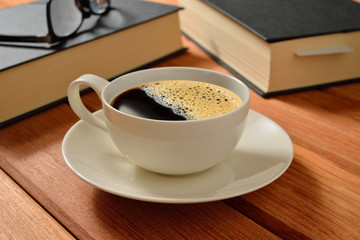 Cup of coffee and books on wooden table