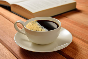 Cup of coffee and books on wooden table