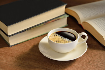 Cup of coffee and books on wooden table