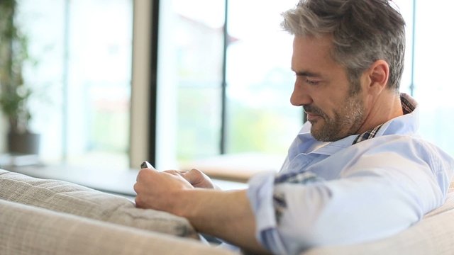 Mature man sending message with smartphone