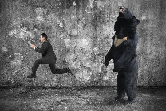 Businessman Holding Tablet Running From An Angry Bear