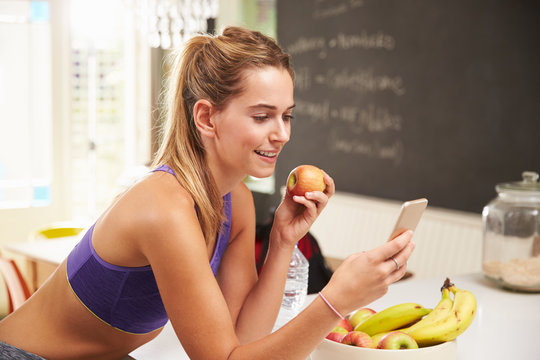 Woman Wearing Gym Clothing Looking At Mobile Phone