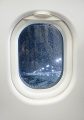 Airplane window view at night with raindrop