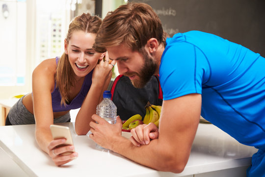 Couple Wearing Gym Clothing Reading Message On Mobile Phone
