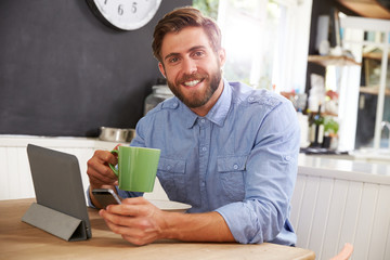 Man Eating Breakfast Whilst Using Digital Tablet And Phone