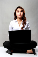 Young businesswoman thinking while working with a laptop