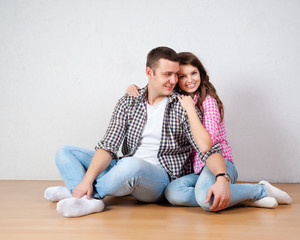Fototapeta na wymiar Portrait Of Happy Young Couple Sitting On Floor 
