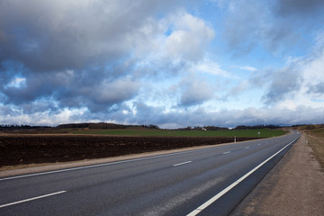 Cloudy landscape with asphalt road, Latvia, Europe.