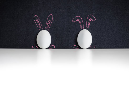 Two white easter eggs on a chackboard