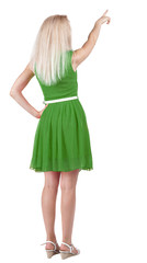 Back view of young blonde woman pointing at wall.