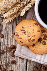 Cup of coffee with cookies and wheat on a wooden table.