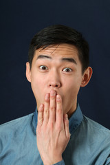 Young Asian man covering his mouth with his palm