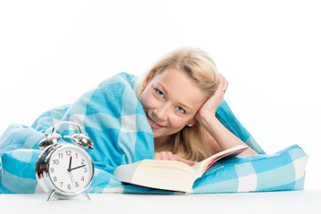 Blonde Frau liegt im Bett und liest ein Buch