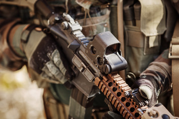 Fototapeta na wymiar solder in gloves holding assault automatic rifle
