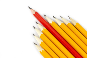 One red pencil standing out from the row of yellow pencils