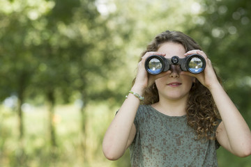 Pretty young girl exploring the environment with a binocular
