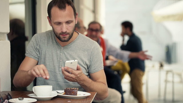 Young man taking photo of food with cellphone sitting in cafe