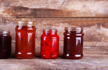 Homemade jars of fruits jam on rustic wooden background