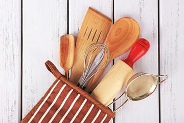 Set of kitchen utensils in mitten on wooden background