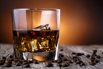 Glass of whiskey with ice and coffee beans.