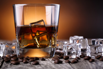 Glass of whiskey with ice and coffee beans.