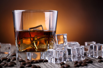 Glass of whiskey with ice and coffee beans.