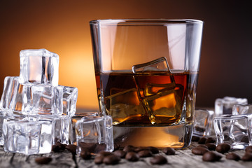 Glass of whiskey with ice and coffee beans.