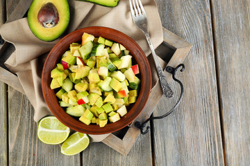 Salad with apple and avocado in bowl on tray on table close up