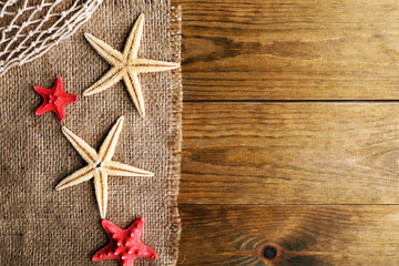 Sea stars on sackcloth on wooden background