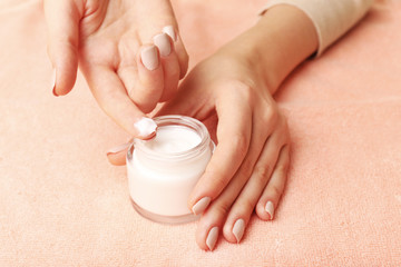 Female hands with jar of cream on fabric background