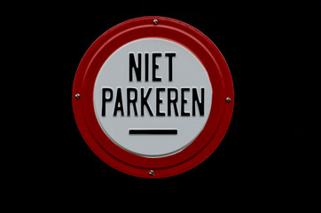 Sign warning against parking, on a painted black background