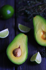 Sliced avocado with lime and herb on wooden table, closeup