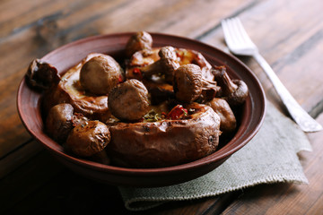 Baked potatoes with mushrooms in bowl on table close up