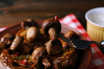 Baked potatoes with mushrooms in bowl and sauce