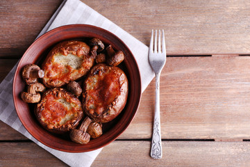 Baked potatoes with mushrooms in bowl on wooden table