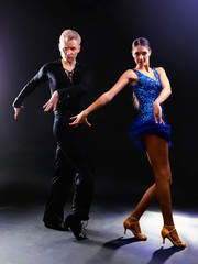Beautiful couple of professional artists dancing on black background