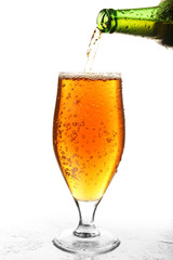 Pouring beer from bottle into glass isolated on white