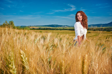 Portrait of a woman on golden cereal field in summer